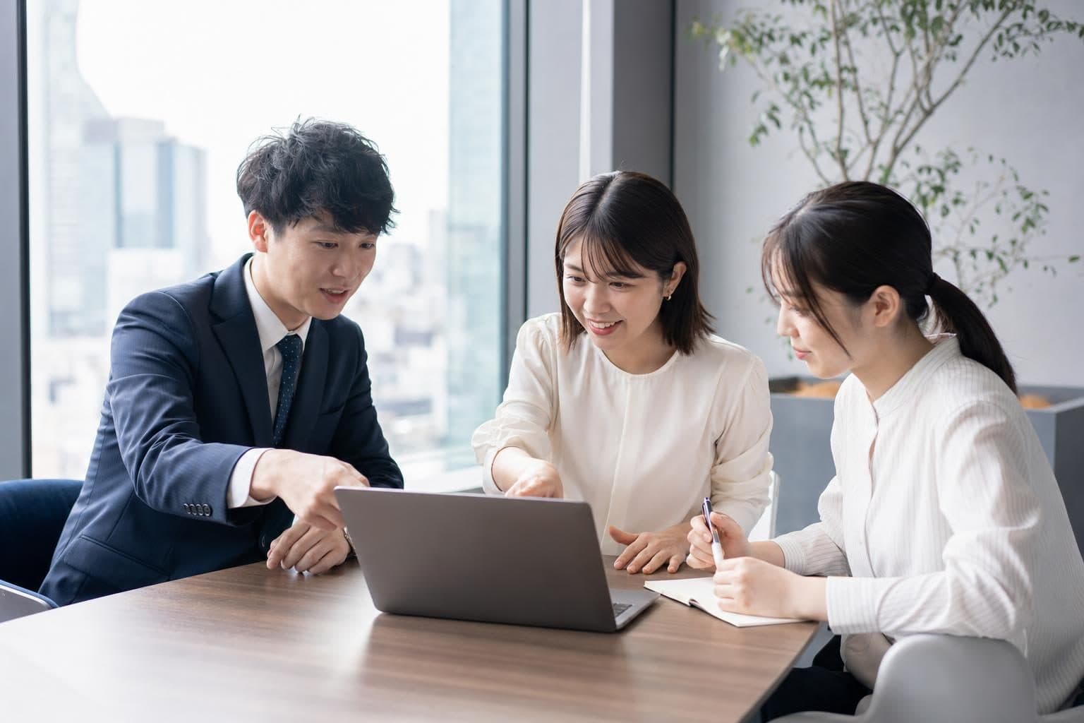 ノートPCを囲み、資料について話し合う3人